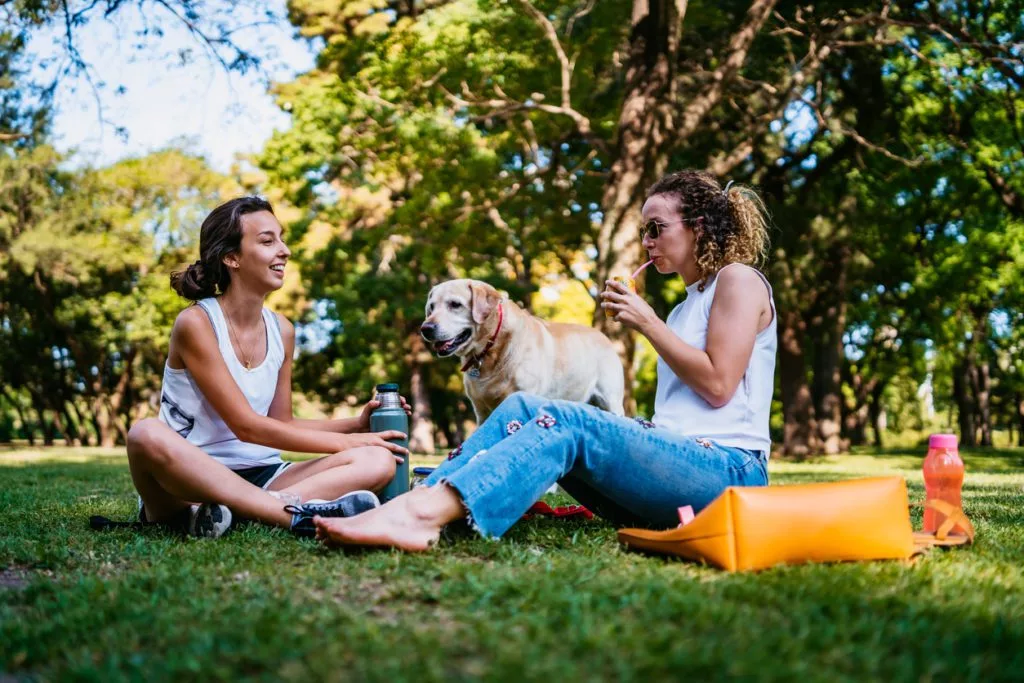 Two women and dog relaxing in park